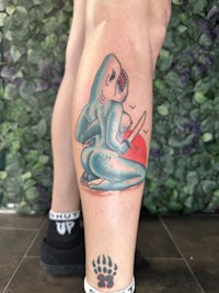 a tattoo of a shark on a person's leg