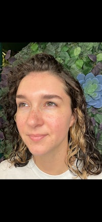 a woman with curly hair standing in front of a green wall